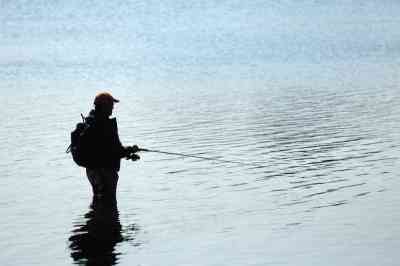 湖にウェーディングをしながら釣りをしている男性の写真