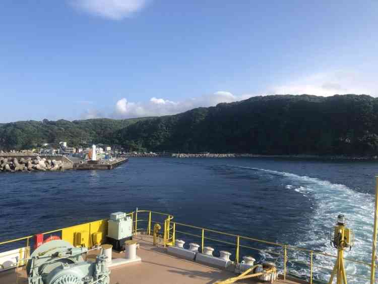 伊豆大島の岡田港から出船する船尾からの写真。奥には堤防が見える。