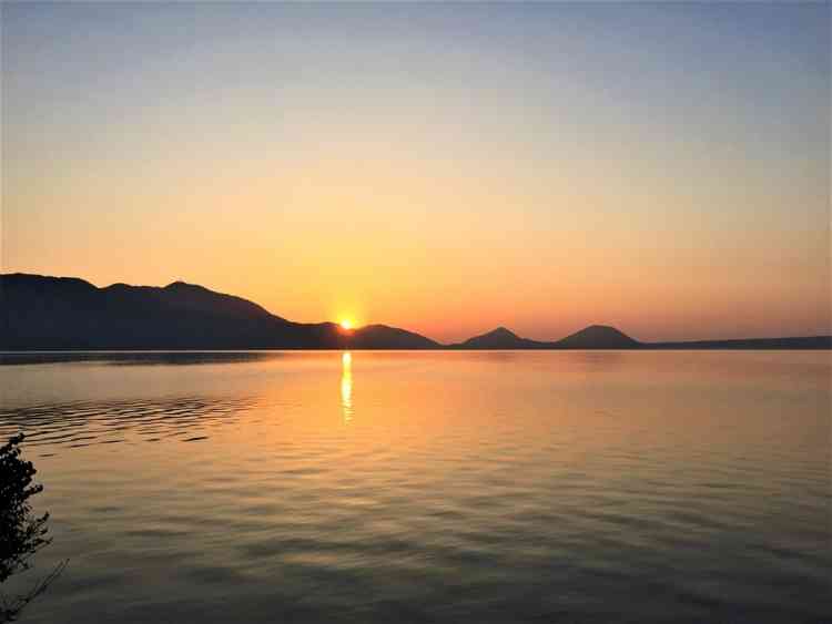 支笏湖の夕陽。水面にオレンジ色の美しい光が反射している。